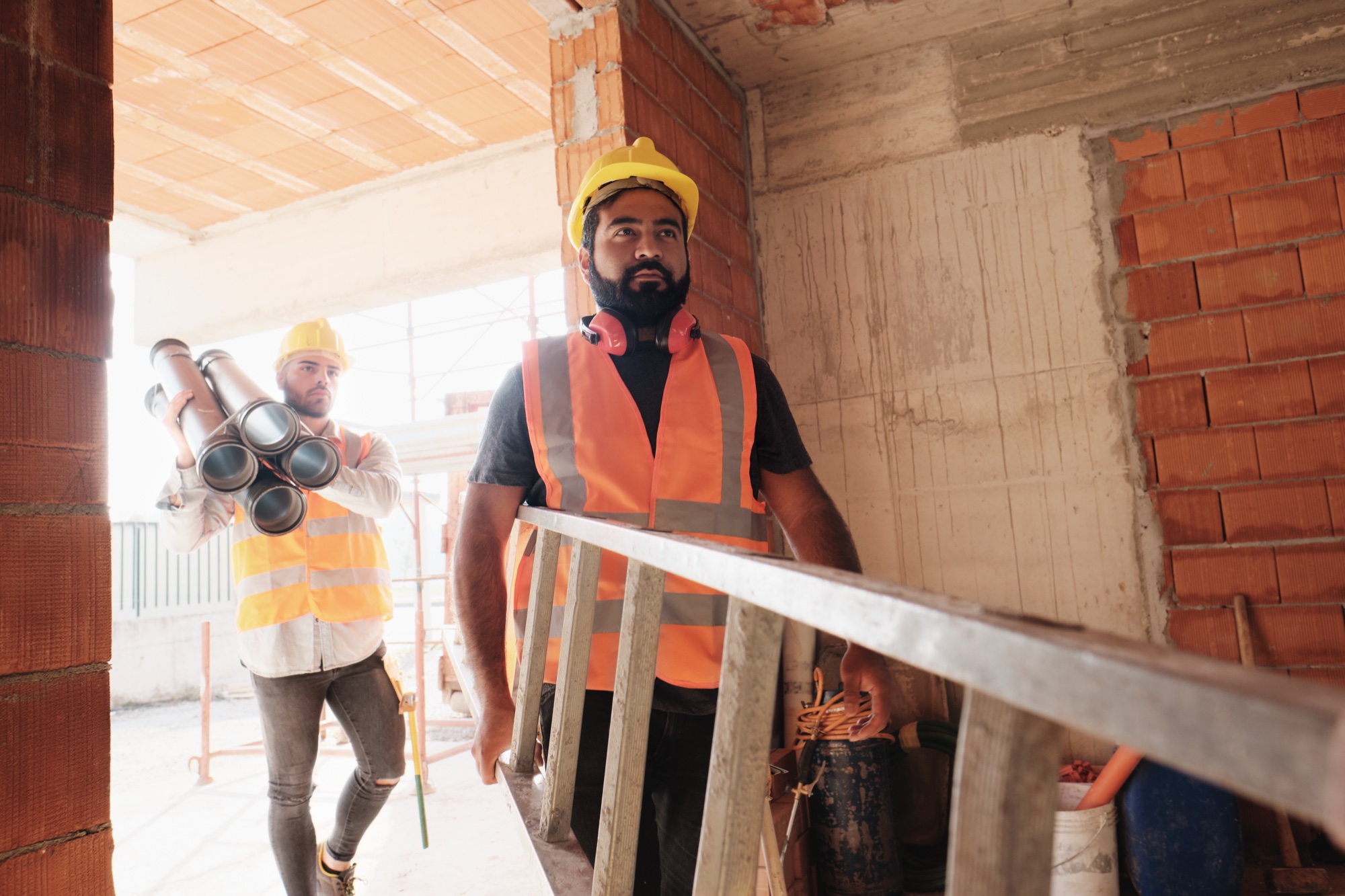 Trabajadores en obra con escalera y tubería